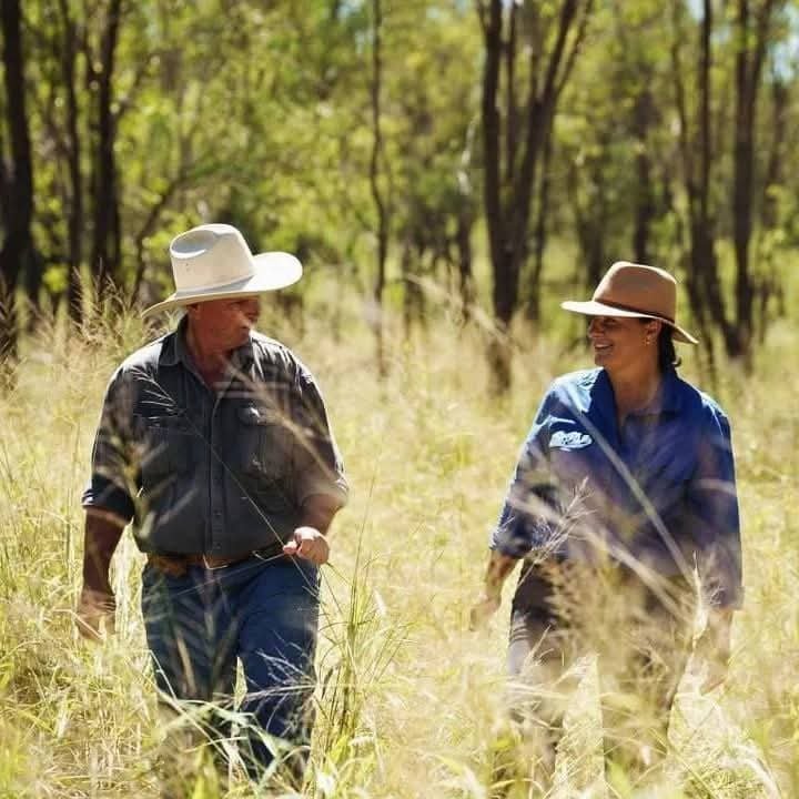 Andrew and Meagan Lawrie walking through tall grass on their farm